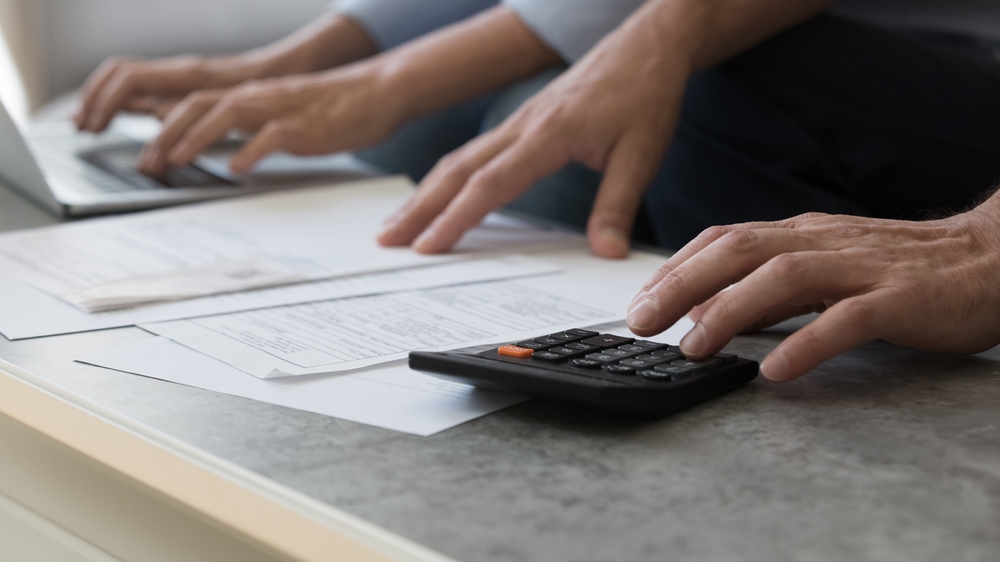 two people using a calculator and reviewing documents